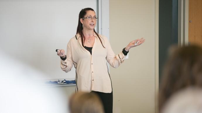 Carolyn Becker stands in front of a whiteboard in the CSI Treehouse holding a marker