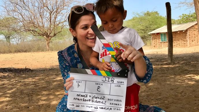 Nava Kavelin hugs a child while he plays with a movie clapboard