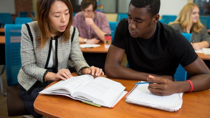 photo of a professor reviewing a text book with a student