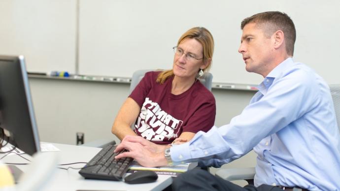 One employee training another employee on a computer