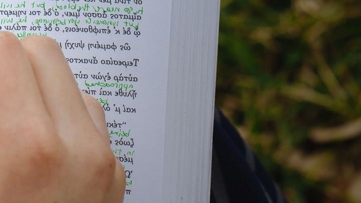 语言学 student adds handwritten notes to his book.