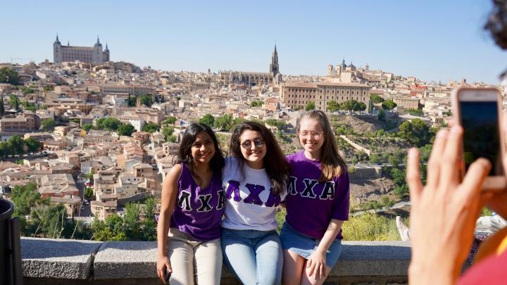 three students sitting on ledge in madrid