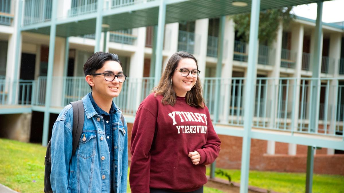 two students walk next to a bridge between two residence halls